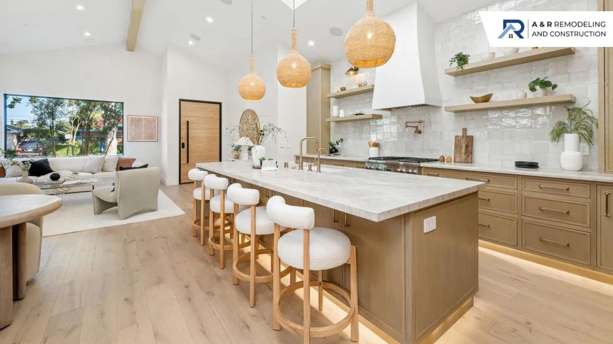 A modern kitchen with a large wooden island, a white countertop, and five white bar stools under three woven pendant lights.