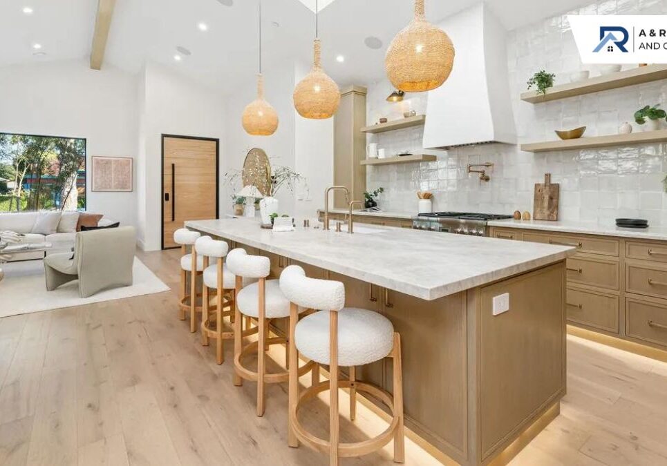 A modern kitchen with a large wooden island, a white countertop, and five white bar stools under three woven pendant lights.